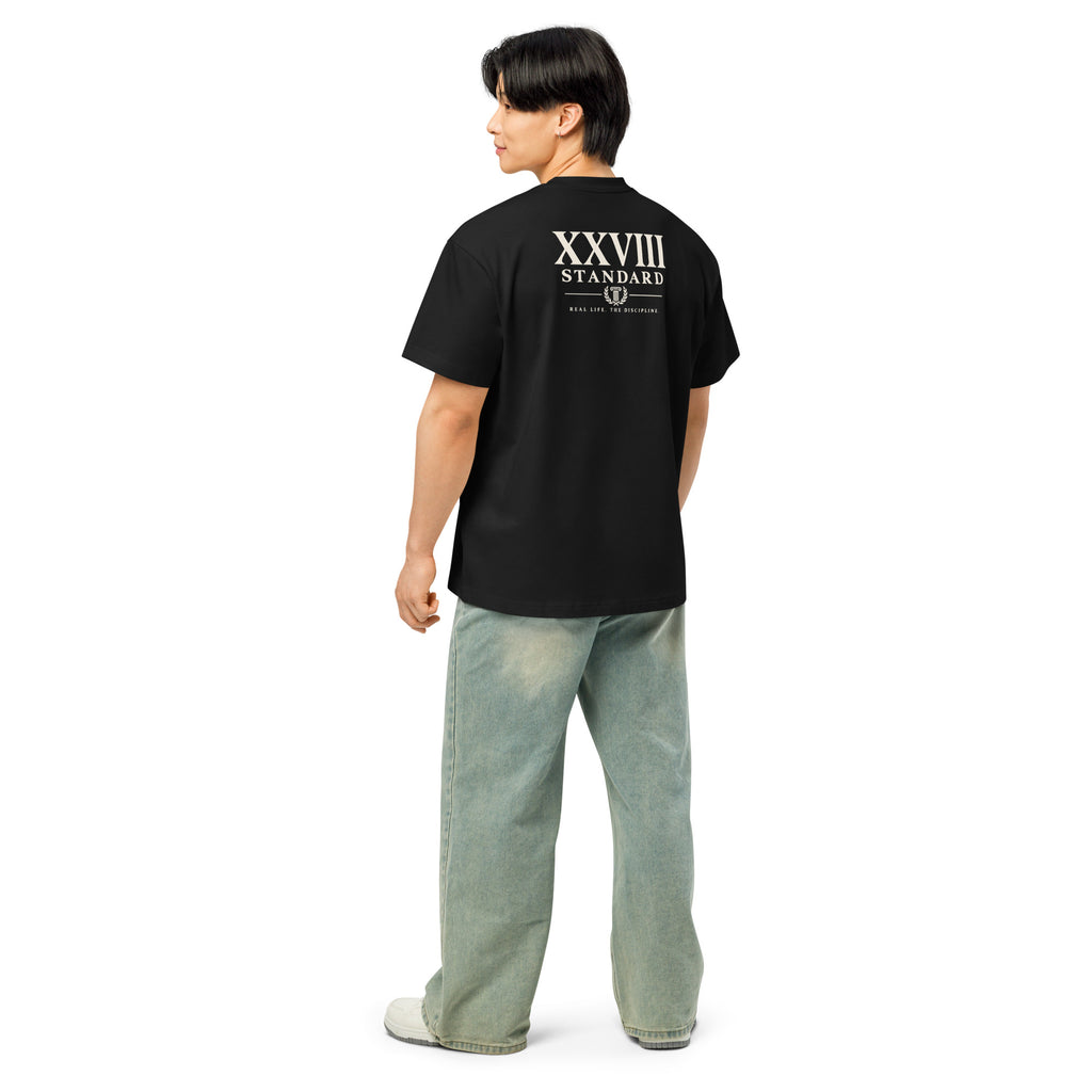 A man shown from the back wearing a black short-sleeve t-shirt with a white graphic print reading 'XXVIII STANDARD' on the upper back, paired with light-wash wide-leg jeans and white sneakers, against a plain white background.